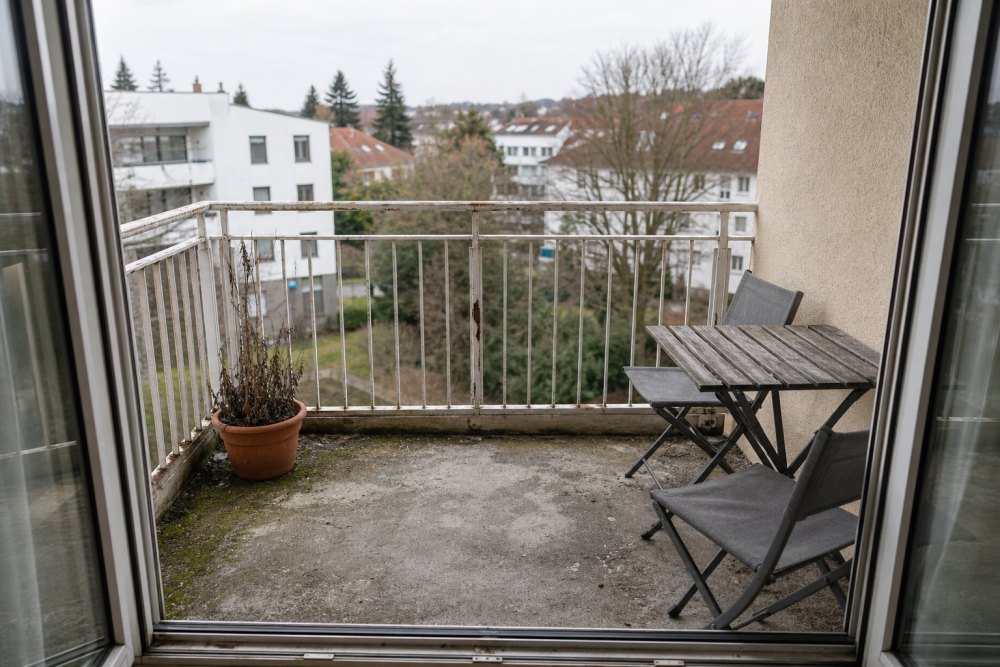 Balkon vor den Malerarbeiten – abblätternder Anstrich am Geländer, verschmutzter Boden und abgestorbene Pflanze